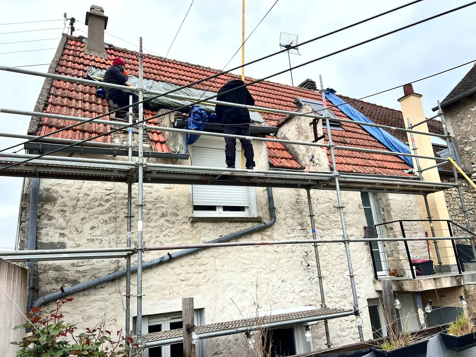 Une maison de village en pierre en cours de réfection de toiture, échafaudage monté